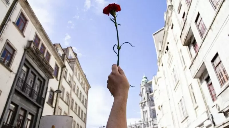 Una mujer sostiene un clavel rojo durante una manifestación para conmemorar el aniversario de la Revolución de los Claveles, a 25 de abril de 2021, en Oporto.